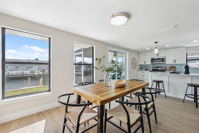 13810 Malcolm Ave, Hudson, FL 34667 - dining area featuring light wood-style flooring, recessed lighting, baseboards, and a water view
