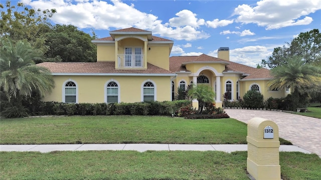 1312 Fishing Lake Dr, Odessa, FL 33556 - mediterranean / spanish house featuring a front lawn, driveway, a chimney, a balcony, and stucco siding