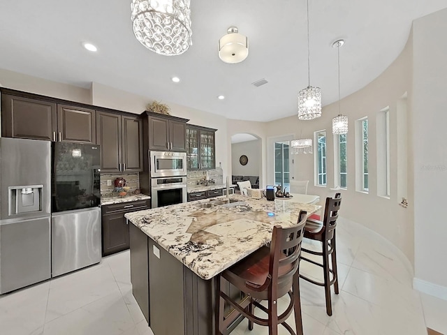 1312 Fishing Lake Dr, Odessa, FL 33556 - kitchen featuring arched walkways, a notable chandelier, marble finish floor, and stainless steel appliances