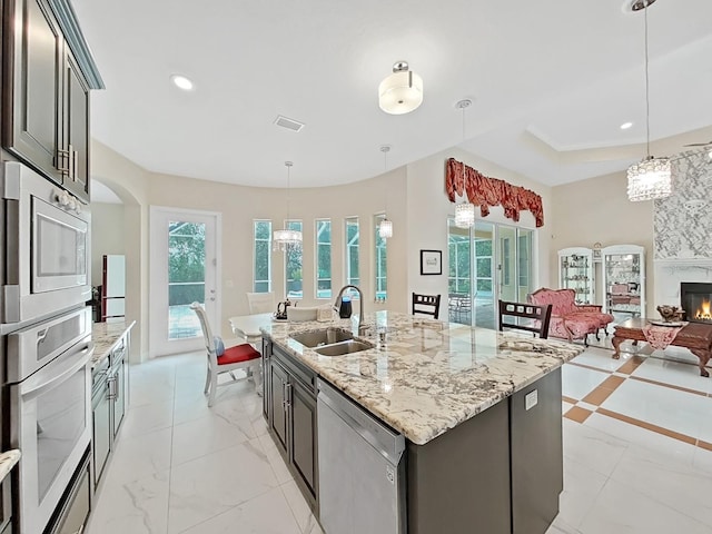1312 Fishing Lake Dr, Odessa, FL 33556 - kitchen featuring open floor plan, a sink, pendant lighting, appliances with stainless steel finishes, and a large fireplace