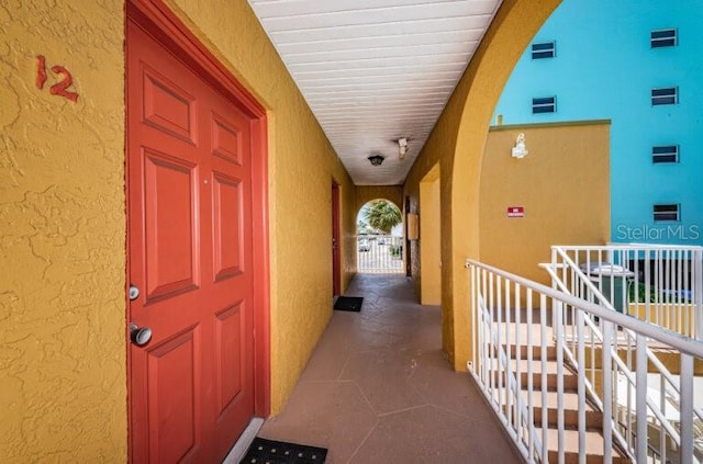 hallway with tile patterned flooring, a textured wall, and an upstairs landing