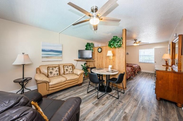 living room featuring a ceiling fan, a textured ceiling, vaulted ceiling, wood finished floors, and baseboards