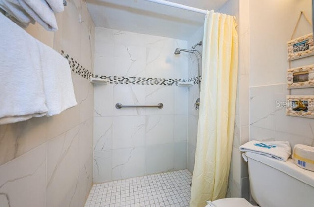 full bath with tile walls, a tile shower, and toilet