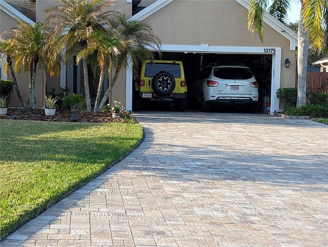 view of front facade with a garage, a front lawn, decorative driveway, and stucco siding