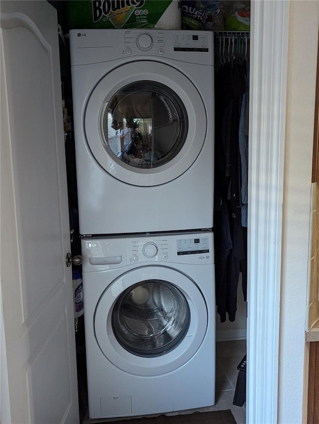 laundry area featuring tile patterned floors, stacked washer / dryer, and laundry area