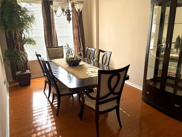 dining space featuring baseboards, wood finished floors, and an inviting chandelier