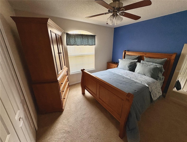bedroom featuring a ceiling fan, light carpet, and a textured ceiling