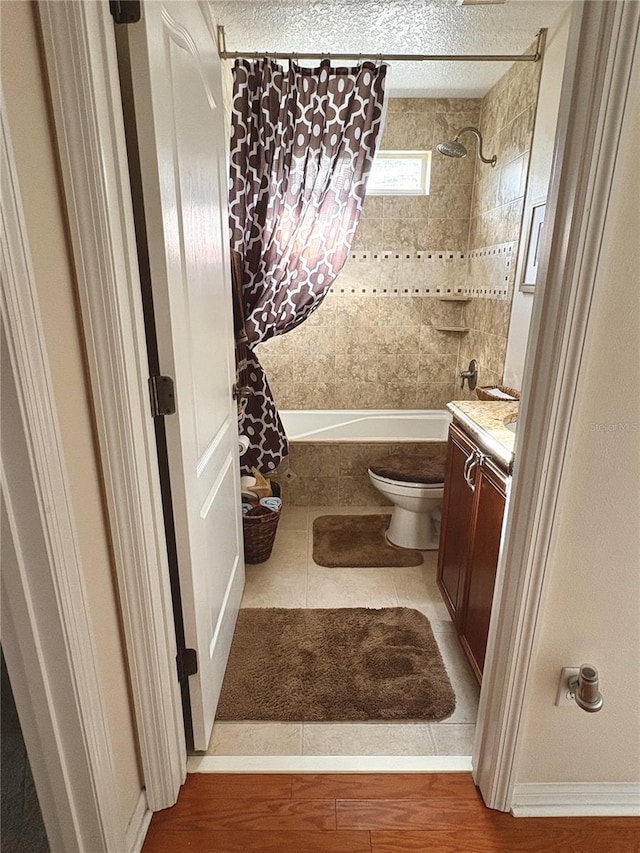 bathroom with wood finished floors, tiled shower / bath combo, toilet, and vanity