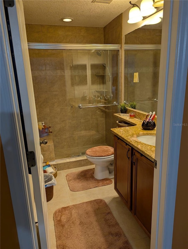 bathroom with toilet, a textured ceiling, a shower stall, and vanity