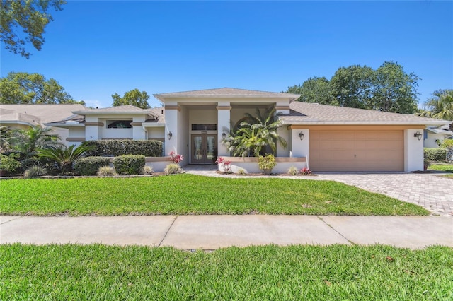 view of front of house featuring an attached garage, french doors, a front yard, and stucco siding