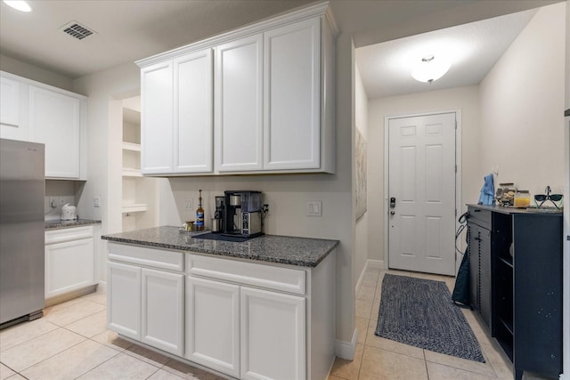 6225 Scarlet Darter Way, Tampa, FL 33625 - kitchen with freestanding refrigerator, light tile patterned flooring, white cabinetry, and dark stone countertops