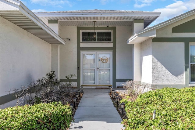 doorway to property with stucco siding and roof with shingles