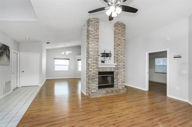 unfurnished living room with wood finished floors, visible vents, a fireplace, and ceiling fan