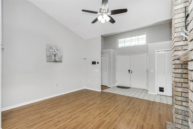 entryway with light wood-type flooring, a ceiling fan, baseboards, and vaulted ceiling