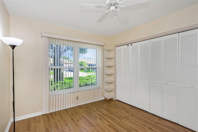 unfurnished bedroom featuring light wood-style floors, a closet, a ceiling fan, and baseboards