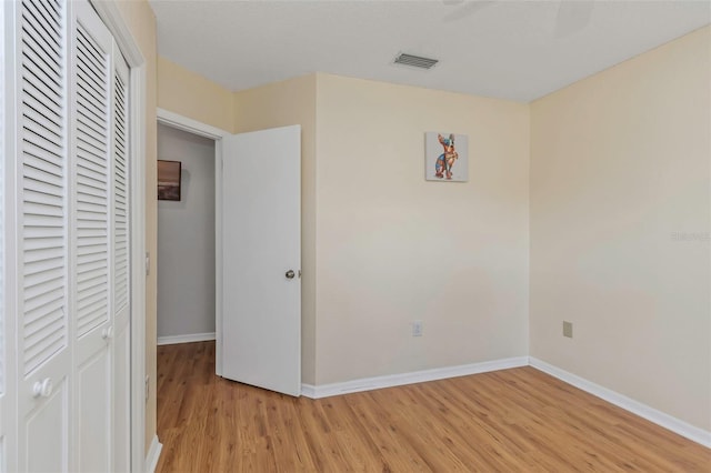 unfurnished bedroom with light wood finished floors, baseboards, visible vents, and a closet