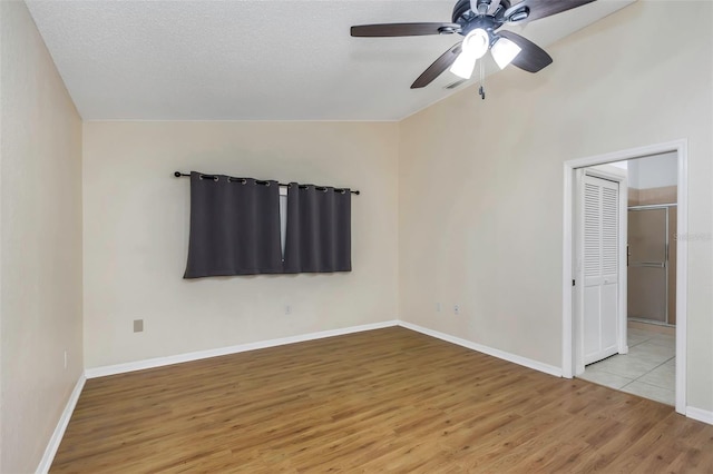 unfurnished bedroom with wood finished floors, lofted ceiling, baseboards, and ceiling fan