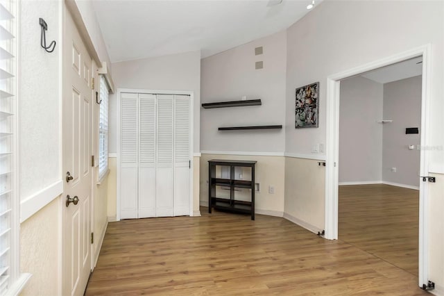 interior space with lofted ceiling, baseboards, and wood finished floors