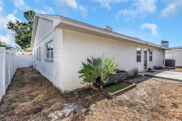 view of property exterior featuring a fenced backyard, cooling unit, and stucco siding