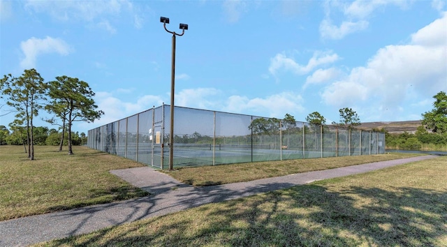 view of sport court with fence and a yard