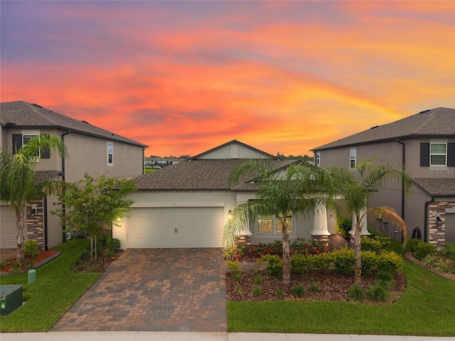5059 Bromeliad Ave, Wimauma, FL 33598 - view of front facade with decorative driveway, an attached garage, stucco siding, and a yard