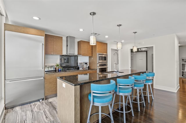 175 1st St S Unit 2603, Saint Petersburg, FL 33701 - kitchen with wall chimney range hood, brown cabinets, built in appliances, a sink, and visible vents