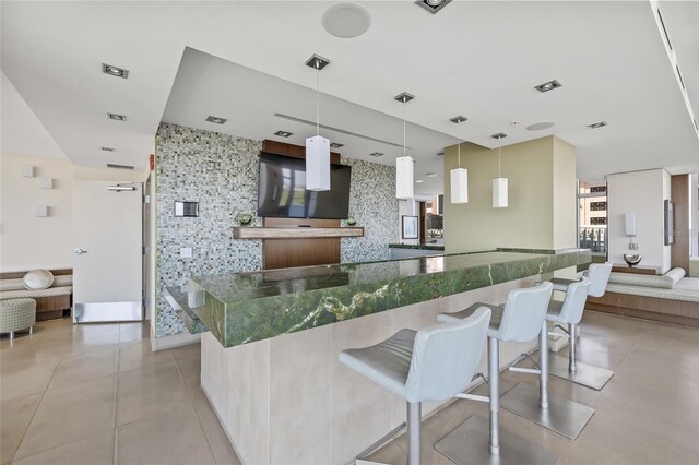 175 1st St S Unit 2603, Saint Petersburg, FL 33701 - kitchen featuring decorative backsplash, a kitchen bar, dark stone countertops, decorative light fixtures, and open floor plan