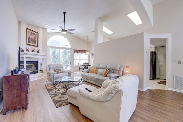 6410 Beaver Way, Tampa, FL 33625 - living room featuring a tiled fireplace, a ceiling fan, light wood finished floors, and visible vents