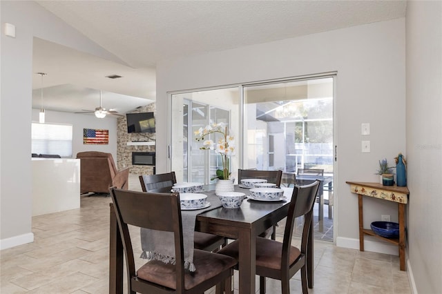1916 Sandstone Pl, Clearwater, FL 33760 - dining space featuring a ceiling fan, a fireplace, vaulted ceiling, baseboards, and light tile patterned flooring