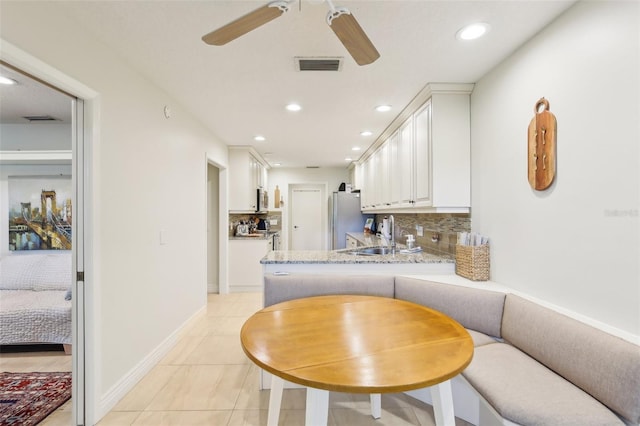 kitchen with white cabinetry, stainless steel appliances, ceiling fan, and backsplash