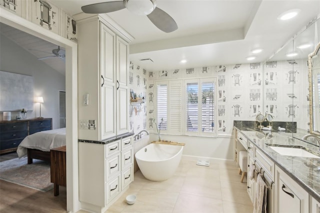 bathroom with recessed lighting, tile patterned floors, a ceiling fan, a freestanding bath, and baseboards