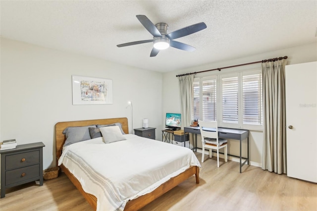 bedroom with a textured ceiling, baseboards, light wood-type flooring, and a ceiling fan