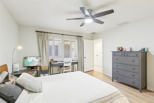 bedroom with light wood-type flooring, ceiling fan, visible vents, and a textured ceiling