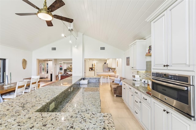 kitchen with a ceiling fan, visible vents, white cabinetry, open floor plan, and oven