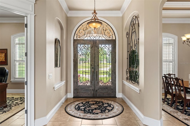 tiled foyer entrance with a chandelier, baseboards, ornamental molding, arched walkways, and french doors