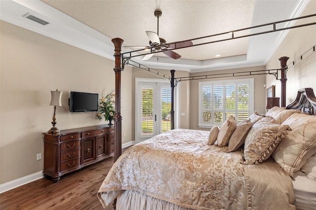 bedroom with a raised ceiling, access to exterior, visible vents, baseboards, and wood finished floors