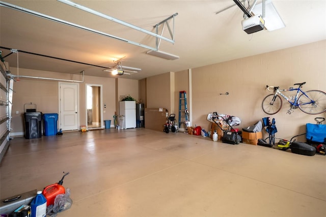 garage featuring concrete block wall, freestanding refrigerator, and a garage door opener