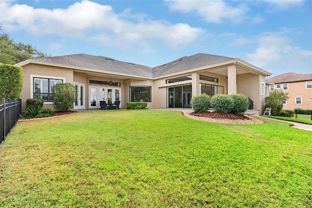 back of property featuring a yard, a ceiling fan, stucco siding, french doors, and fence