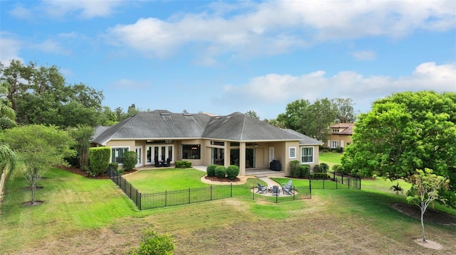 rear view of property featuring a patio area, a lawn, stucco siding, french doors, and fence