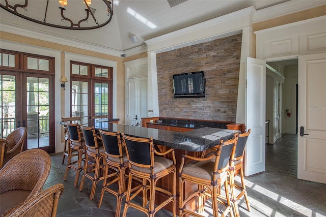 dining room featuring a high ceiling, stone tile floors, french doors, and indoor bar