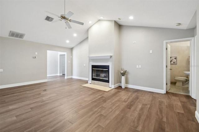 17 Bellevue Dr, Treasure Island, FL 33706 - unfurnished living room with ceiling fan, a fireplace with flush hearth, wood finished floors, high vaulted ceiling, and baseboards
