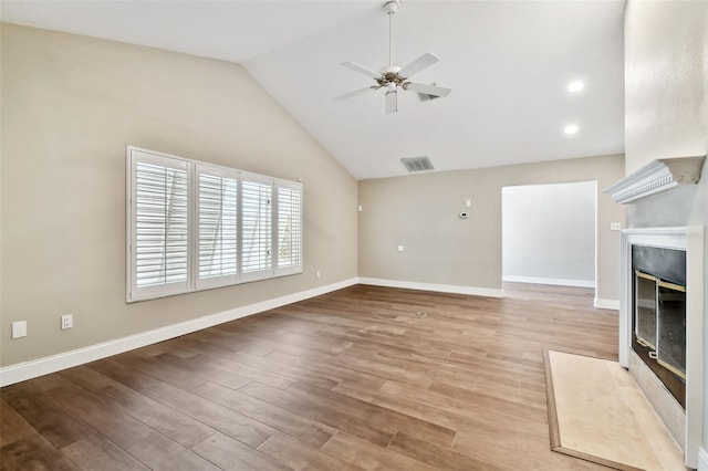 17 Bellevue Dr, Treasure Island, FL 33706 - unfurnished living room with a fireplace with flush hearth, a ceiling fan, wood finished floors, vaulted ceiling, and baseboards