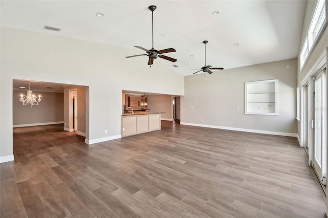 17 Bellevue Dr, Treasure Island, FL 33706 - unfurnished living room with a chandelier, high vaulted ceiling, a ceiling fan, baseboards, and wood finished floors