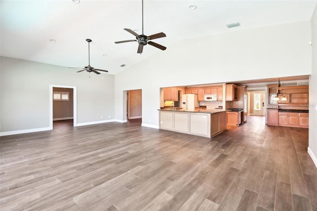 17 Bellevue Dr, Treasure Island, FL 33706 - unfurnished living room with high vaulted ceiling, ceiling fan, baseboards, light wood-type flooring, and healthy amount of natural light