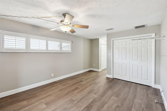 17 Bellevue Dr, Treasure Island, FL 33706 - unfurnished bedroom with wood finished floors, a closet, baseboards, a textured ceiling, and ceiling fan