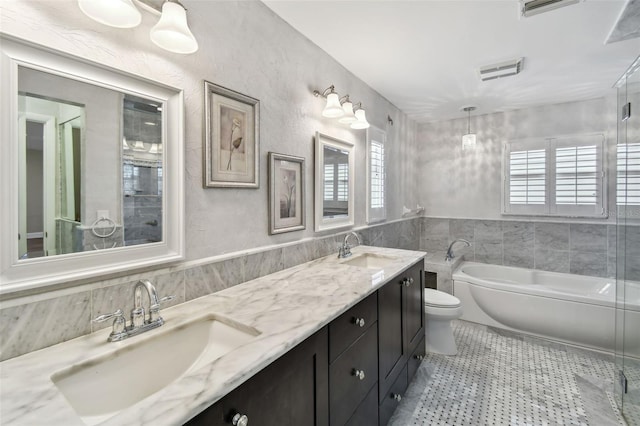 17 Bellevue Dr, Treasure Island, FL 33706 - full bathroom with tile walls, a bath, toilet, double vanity, and a wainscoted wall