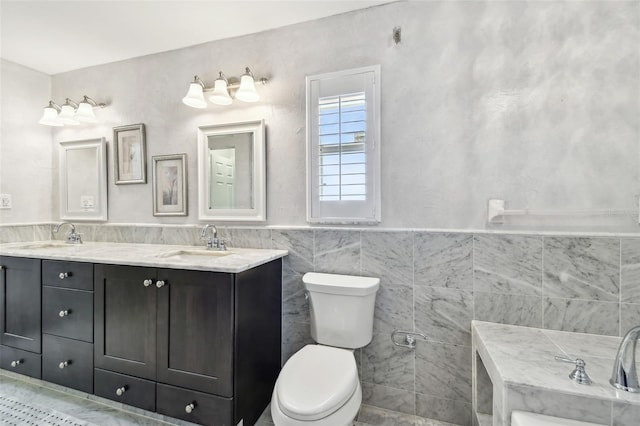 17 Bellevue Dr, Treasure Island, FL 33706 - bathroom with tile walls, double vanity, toilet, wainscoting, and tile patterned floors