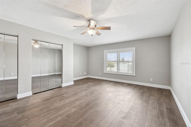 17 Bellevue Dr, Treasure Island, FL 33706 - unfurnished bedroom with multiple closets, wood finished floors, baseboards, ceiling fan, and a textured ceiling