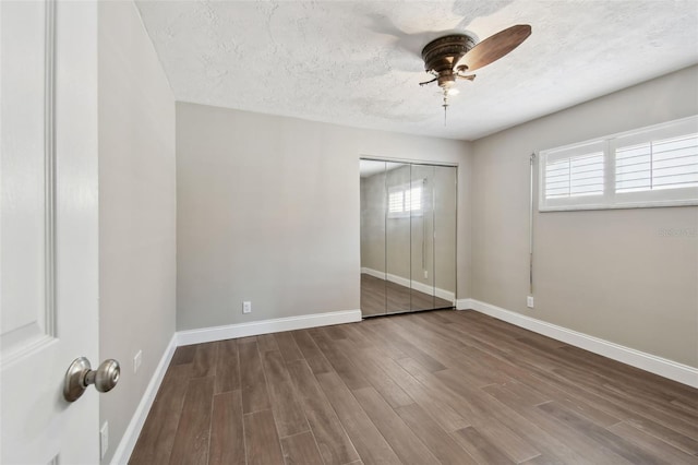 17 Bellevue Dr, Treasure Island, FL 33706 - unfurnished bedroom with wood finished floors, baseboards, a textured ceiling, a closet, and ceiling fan
