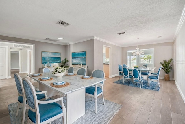 17 Bellevue Dr, Treasure Island, FL 33706 - dining space featuring light wood-style floors, a chandelier, baseboards, a textured ceiling, and ornamental molding